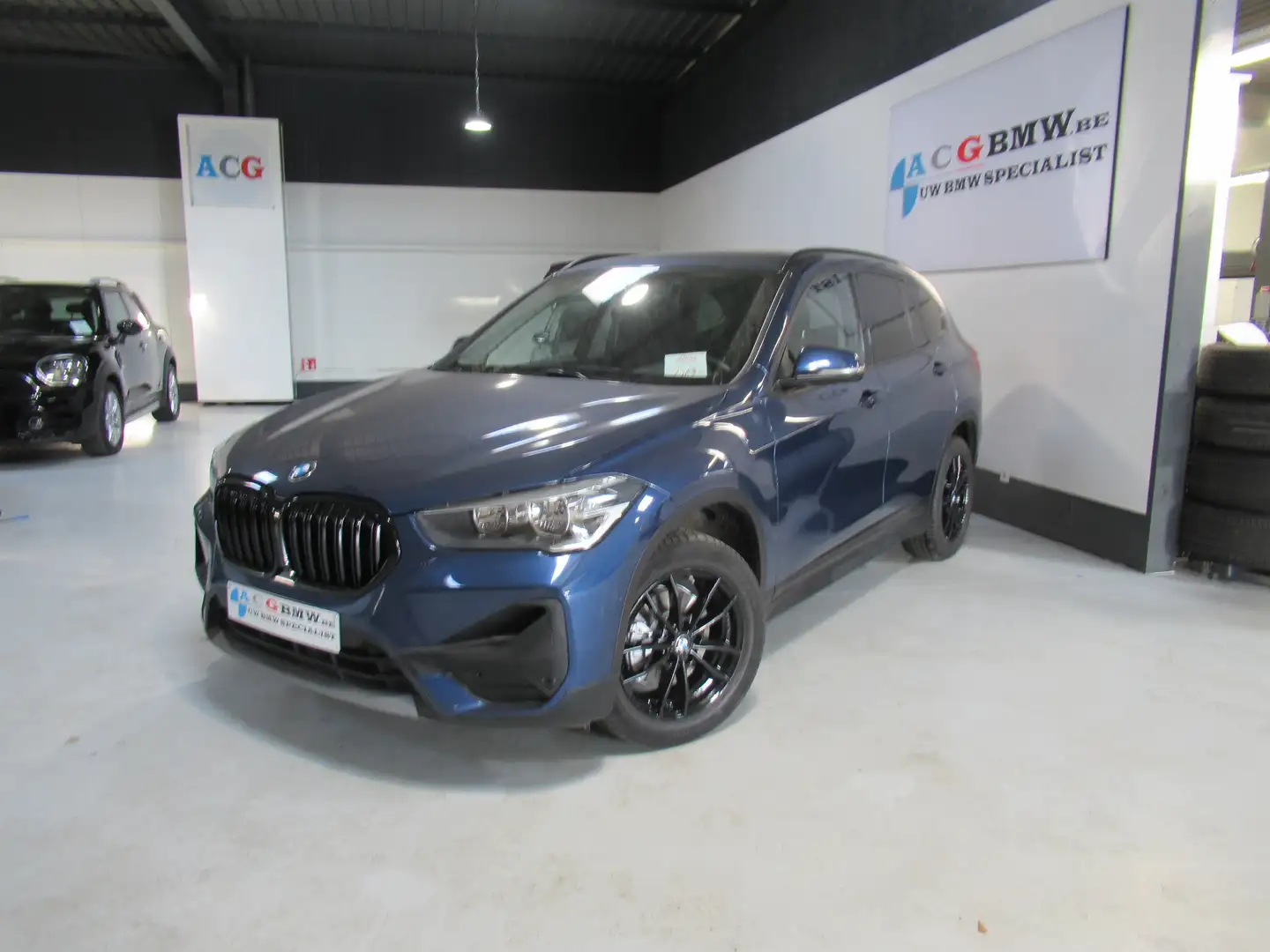 BMW X1 18i Aut PanoDak Trekh Navi Carplay ParkAss Black Blauw - 1
