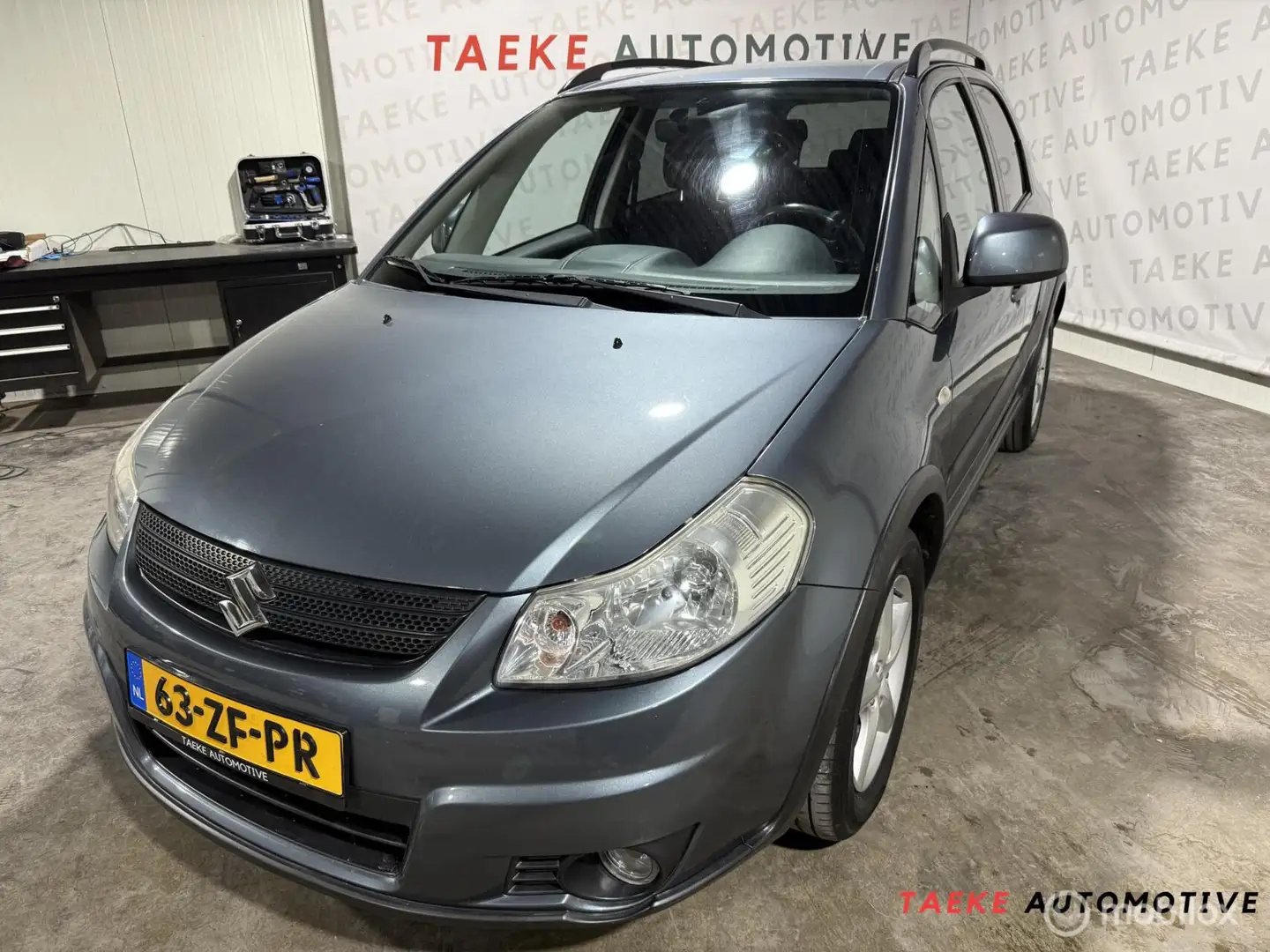 Suzuki SX4 1.6 Shogun Airco/Cruise/Nap/Parkeersen Grau - 1